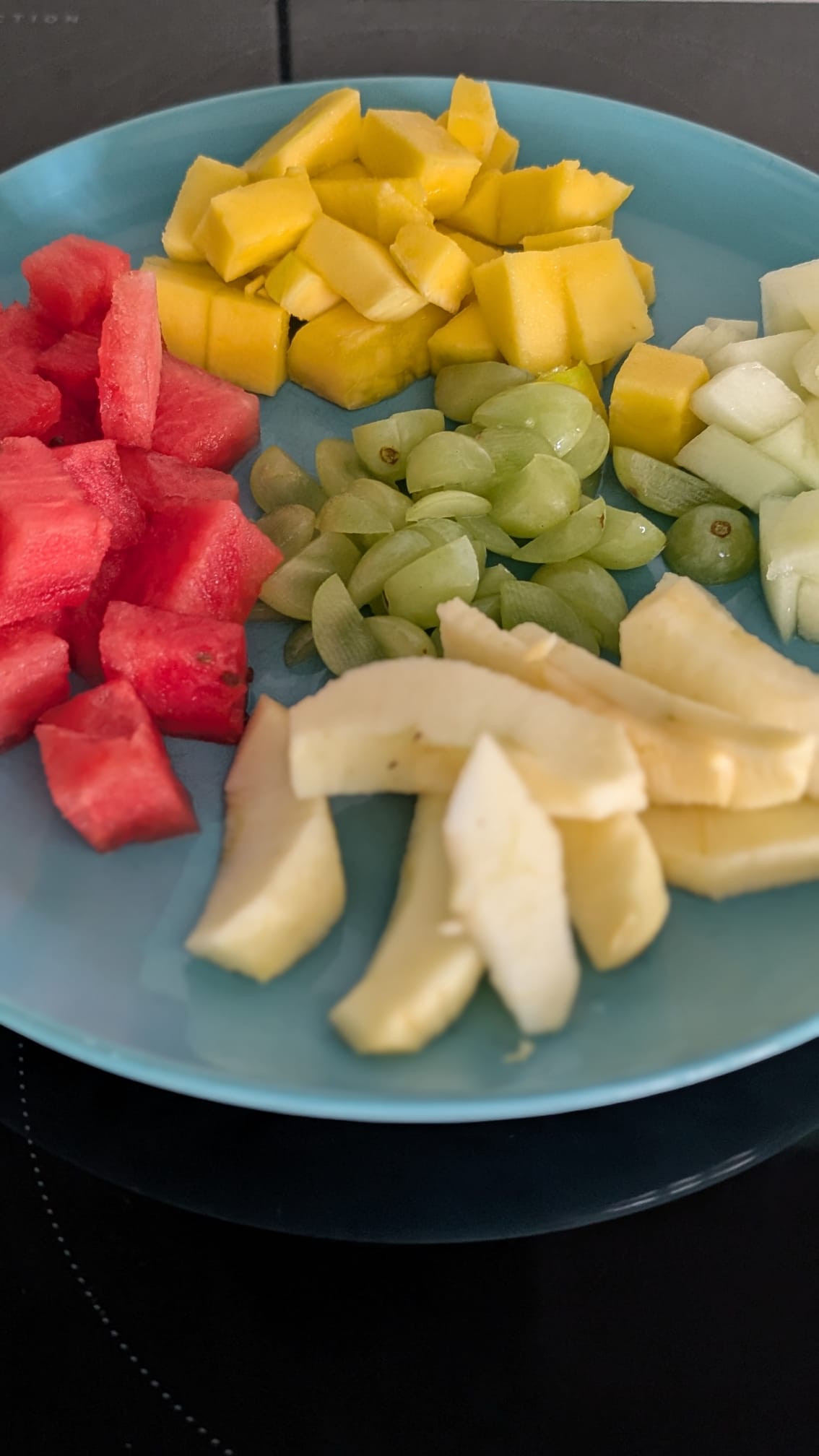 Liebevoll angerichteter Obstteller mit Wassermelone, Mango, Trauben, Melone und Apfel